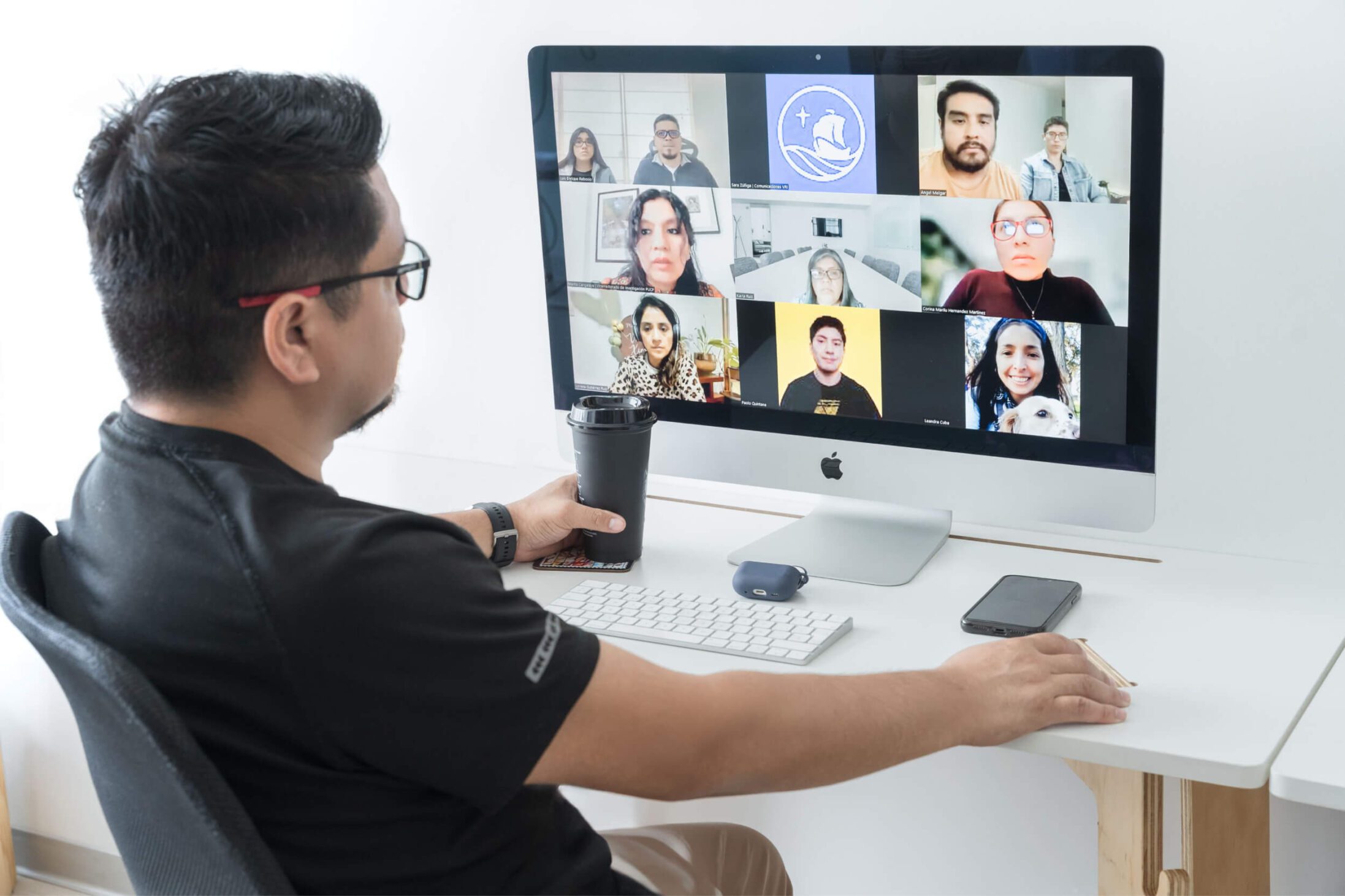 Hombre frente a una computadora en una reunión virtual con clientes.